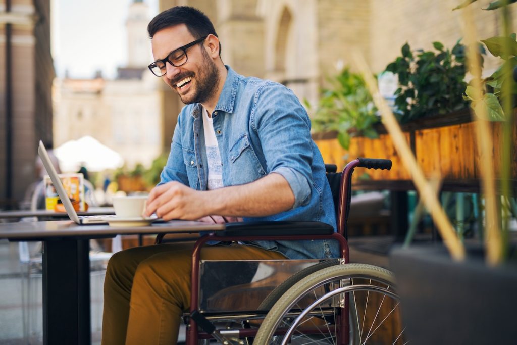 Handicapped man in cafe Smiling man in a wheelchair sitting in cafe and drinking coffee.