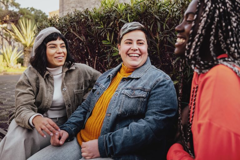 Group of diverse cheerful women friends sitting in outdoors in a park
