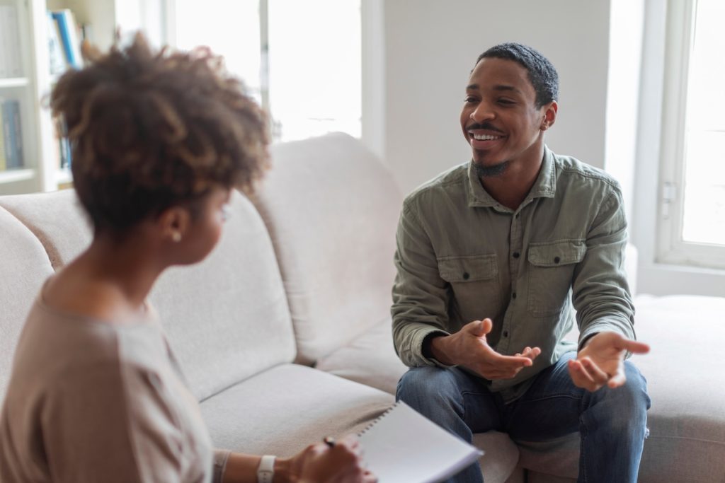 Cheerful positive african american guy having conversation with therapist Cheerful man speaking to a therapist