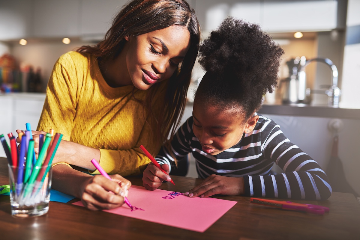 Black mother and daughter drawing in their home