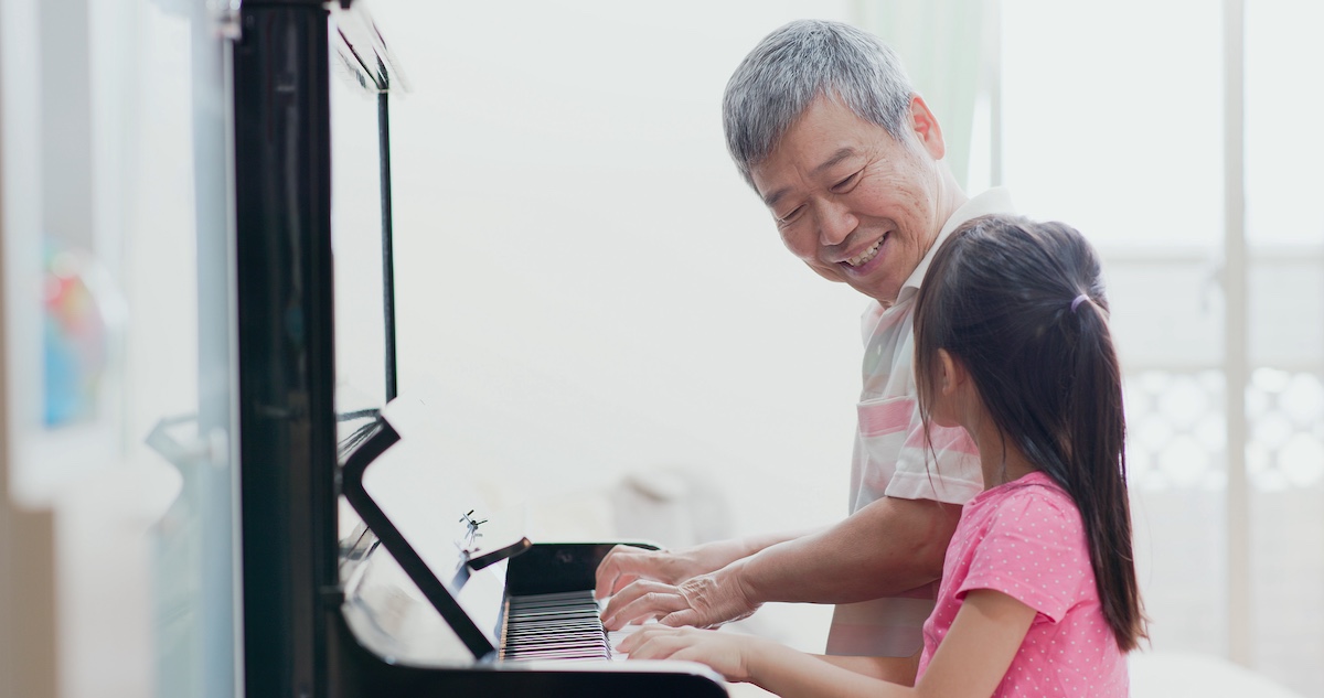 grandfather teach girl playing the piano happily